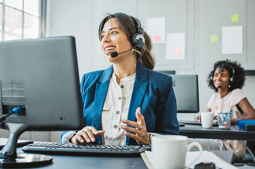 Friendly woman in call center service talking with costumers by headset. Call center and diverse people group in business.